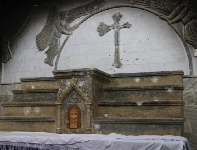 Bullet holes and a defaced cross mar the main altar of St. Addai’s Church in Karemlash. Bullet holes and a defaced cross mar the main altar of St. Addai’s Church in Karemlash.