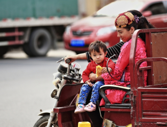 Pair of young Uighur women with child ride an auto rickshaw downstreet-Sunday Market's area. Pair of young Uighur women with child ride an auto rickshaw downstreet-Sunday Market's area.