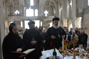 Above, Syriac Orthodox Patriarch of Antioch Ignatius Aphrem II celebrates Holy Qurobo Mass over the ruins of the (Syriac Orthodox) Virgin Mary Church in Deir ez-Zour, Syria.
Below, Patriarch Ignatius Aphrem walks through the streets of the ravaged city. Above, Syriac Orthodox Patriarch of Antioch Ignatius Aphrem II celebrates Holy Qurobo Mass over the ruins of the (Syriac Orthodox) Virgin Mary Church in Deir ez-Zour, Syria.
Below, Patriarch Ignatius Aphrem walks through the streets of the ravaged city.