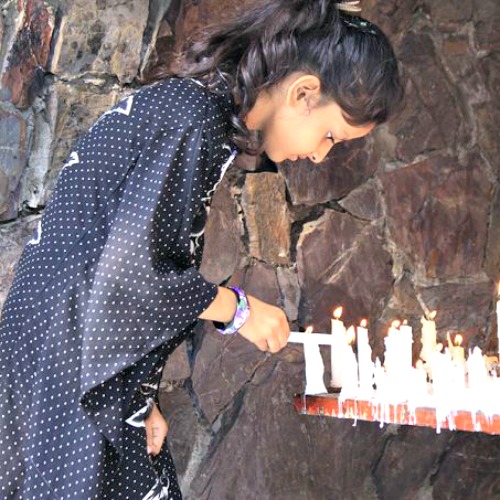 A young girl lights a candle at a Marian grotto in Pakistan. A young girl lights a candle at a Marian grotto in Pakistan.