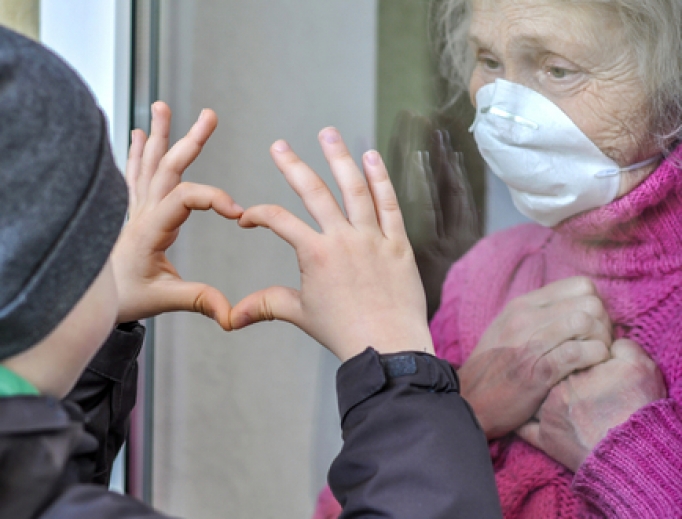 A grandmother in a respiratory mask communicates with her grandchild through a window amid the coronavirus pandemic. A grandmother in a respiratory mask communicates with her grandchild through a window amid the coronavirus pandemic.