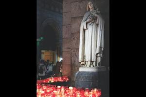 The faithful pray and light candles before a statue of St. Thérèse at Sacre Coeur Basilica in Paris. The faithful pray and light candles before a statue of St. Thérèse at Sacre Coeur Basilica in Paris.