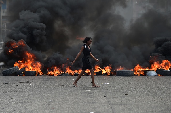 A woman walks past tire barricades set ablaze by demonstrators protesting in Port-au-Prince against Haitian President Jovenel Moise Feb. 10. A woman walks past tire barricades set ablaze by demonstrators protesting in Port-au-Prince against Haitian President Jovenel Moise Feb. 10.