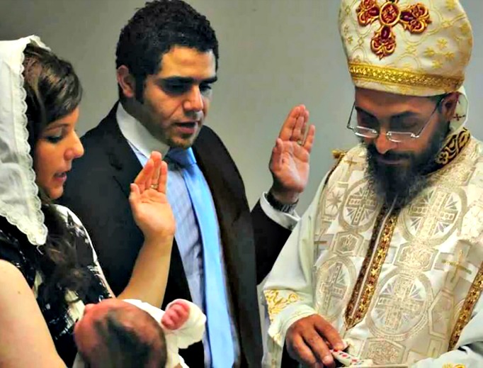 A Coptic Orthodox priest baptizes an infant. A Coptic Orthodox priest baptizes an infant.