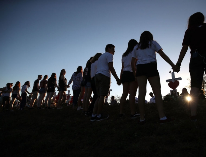 Students and family members holds hands Feb. 18 around a makeshift memorial in front of Marjory Stoneman Douglas High School, where 17 people were killed Feb. 14 in Parkland, Florida. Students and family members holds hands Feb. 18 around a makeshift memorial in front of Marjory Stoneman Douglas High School, where 17 people were killed Feb. 14 in Parkland, Florida.