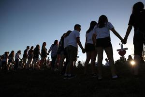 Students and family members holds hands Feb. 18 around a makeshift memorial in front of Marjory Stoneman Douglas High School, where 17 people were killed Feb. 14 in Parkland, Florida. Students and family members holds hands Feb. 18 around a makeshift memorial in front of Marjory Stoneman Douglas High School, where 17 people were killed Feb. 14 in Parkland, Florida.