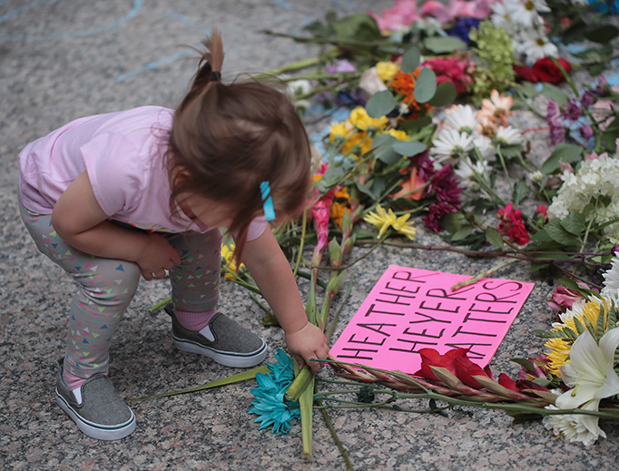 A young girl puts flowers on a memorial to Heather Heyer that was chalked on the pavement during a demonstration on August 13, 2017 in Chicago, Illinois. Heyer was killed and 19 others were injured in Charlottesville, Virginia when a car plowed into a group of activists who were preparing to march in opposition to a nearby white nationalist rally. A young girl puts flowers on a memorial to Heather Heyer that was chalked on the pavement during a demonstration on August 13, 2017 in Chicago, Illinois. Heyer was killed and 19 others were injured in Charlottesville, Virginia when a car plowed into a group of activists who were preparing to march in opposition to a nearby white nationalist rally.