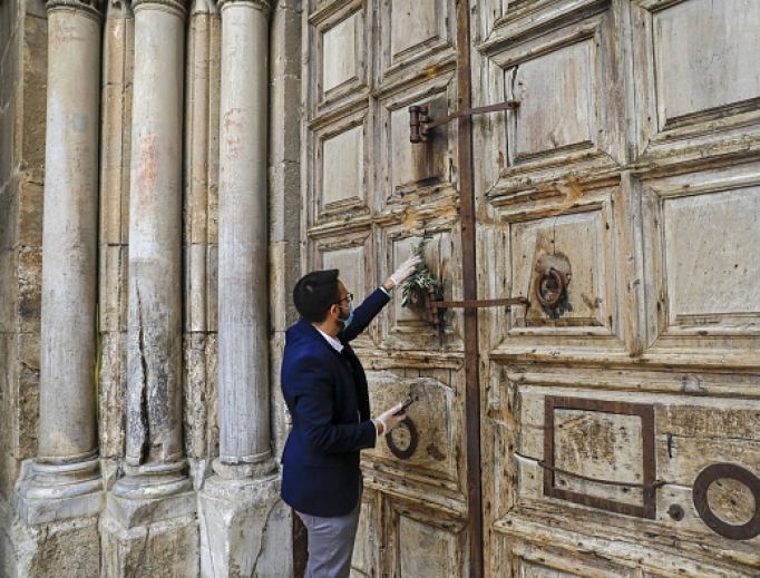 A worshipper hangs an olive branch on the closed door of Holy Sepulcher Church during Palm Sunday in Jerusalem's Old City, amid movement restrictions due to the COVID-19 coronavirus pandemic, on April 5. A worshipper hangs an olive branch on the closed door of Holy Sepulcher Church during Palm Sunday in Jerusalem's Old City, amid movement restrictions due to the COVID-19 coronavirus pandemic, on April 5.