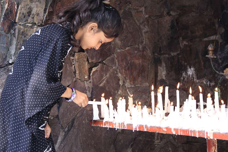 A young girl lights a candle at a Marian grotto in Pakistan. A young girl lights a candle at a Marian grotto in Pakistan.