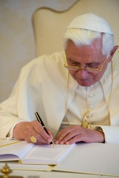 Benedict signs a copy of Caritas in Veritate. Benedict signs a copy of Caritas in Veritate.