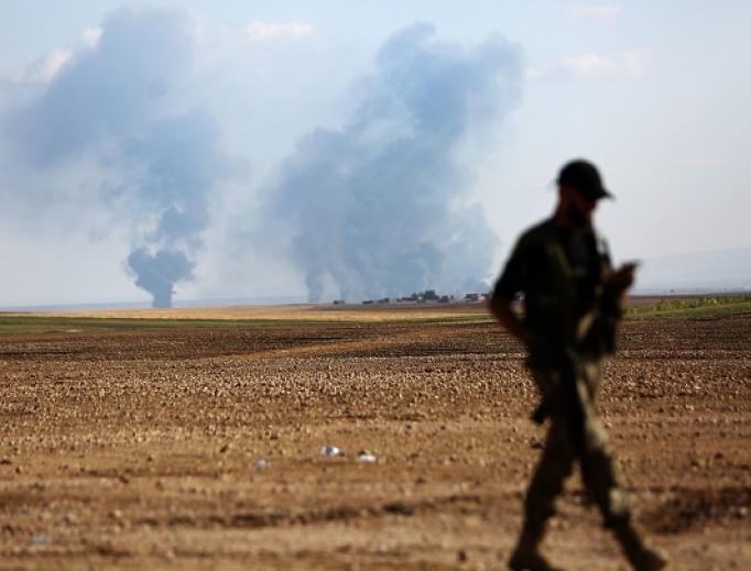 A Turkey-backed Syrian fighter walks as smoke billows in the distance during clashes between Syrian regime forces and Turkish forces near the northeastern town of Ras al-Ein on Oct. 30. A Turkey-backed Syrian fighter walks as smoke billows in the distance during clashes between Syrian regime forces and Turkish forces near the northeastern town of Ras al-Ein on Oct. 30.
