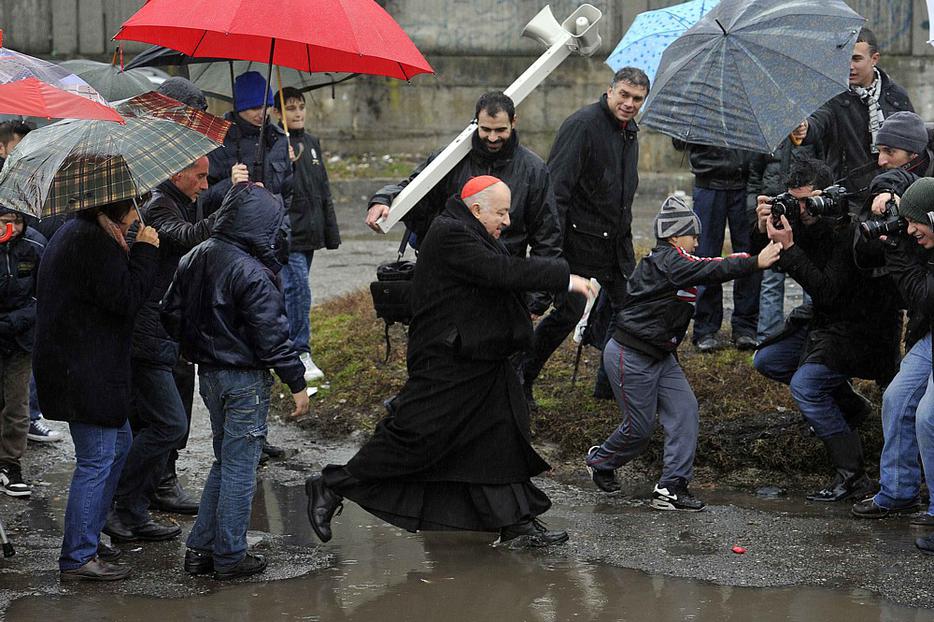 Italian Cardinal Dionigi Tettamanzi of Milan jumps over a puddle during a visit to a Gypsy, or Roma, camp in a Milan neighborhood Dec. 23. 2010. Italian Cardinal Dionigi Tettamanzi of Milan jumps over a puddle during a visit to a Gypsy, or Roma, camp in a Milan neighborhood Dec. 23. 2010.