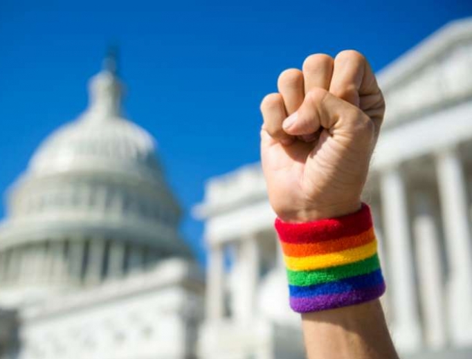 Hand wearing gay pride rainbow wristband making a power fist gesture in front of the US Capitol Building in Washington, DC. Hand wearing gay pride rainbow wristband making a power fist gesture in front of the US Capitol Building in Washington, DC.