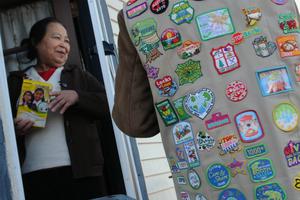 A Girl Scout, wearing her vest covered in badges, sells a box of cookies to a neighbor in Minneapolis. A Girl Scout, wearing her vest covered in badges, sells a box of cookies to a neighbor in Minneapolis.