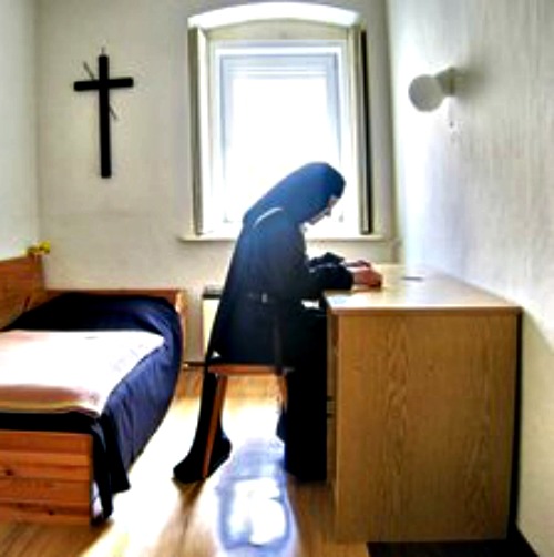 A Carmelite nun meditates on the Bible in her room. A Carmelite nun meditates on the Bible in her room.