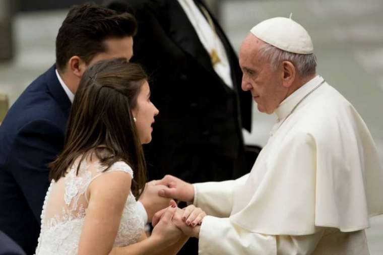 Pope Francis greets a married couple at a Wednesday general audience. Pope Francis greets a married couple at a Wednesday general audience.