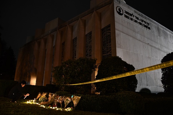 A man kneels to light a candle beneath a police cordon outside the Tree of Life Synagogue after a shooting there left 11 people dead in the Squirrel Hill neighborhood of Pittsburgh Oct. 27. A man kneels to light a candle beneath a police cordon outside the Tree of Life Synagogue after a shooting there left 11 people dead in the Squirrel Hill neighborhood of Pittsburgh Oct. 27.