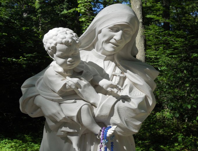 Above, the Mother Teresa of Calcutta Grotto will be dedicated on Sept. 10. Pilgrims often drape rosaries on this statue and others at the shrine. These sacramentals are eventually sent to the missions. Below, Father Harry Brown stands outside of Our Lady of Guadalupe Grotto. After Masses, processions and prayers, joyful pilgrims in costume fill the plaza with singing and folk dancing. Our Lady of Grace Shrine features a statue of Filipino martyr San Lorenzo Ruiz. And a crucifix was erected in memory of people killed in World War I.
Above, the Mother Teresa of Calcutta Grotto will be dedicated on Sept. 10. Pilgrims often drape rosaries on this statue and others at the shrine. These sacramentals are eventually sent to the missions. Below, Father Harry Brown stands outside of Our Lady of Guadalupe Grotto. After Masses, processions and prayers, joyful pilgrims in costume fill the plaza with singing and folk dancing. Our Lady of Grace Shrine features a statue of Filipino martyr San Lorenzo Ruiz. And a crucifix was erected in memory of people killed in World War I.