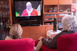 A family follows the Pope's Palm Sunday broadcast from home, April 2020. A family follows the Pope's Palm Sunday broadcast from home, April 2020.