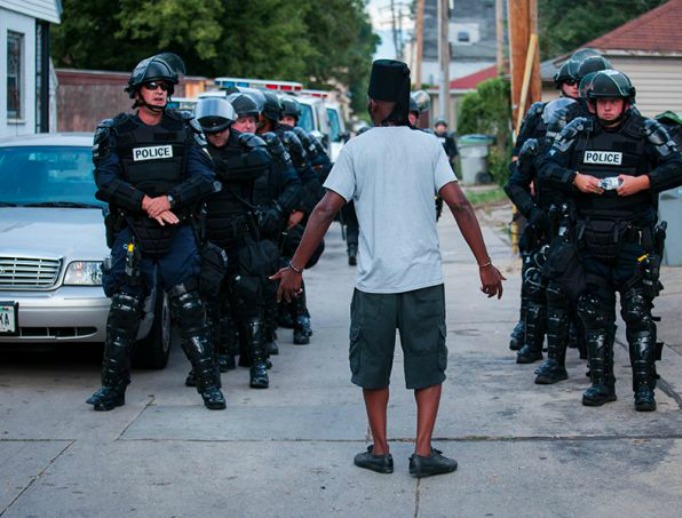 A man talks to police in riot gear as they wait in an alley after a second night of clashes between protestors and police August 15, 2016 in Milwaukee, Wisconsin. A man talks to police in riot gear as they wait in an alley after a second night of clashes between protestors and police August 15, 2016 in Milwaukee, Wisconsin.