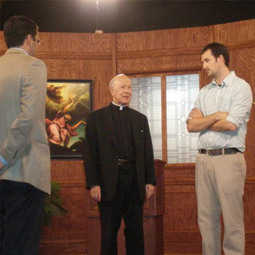 LIGHTS. CAMERA. THEOLOGY! Kevin Gallagher, director of Catholic Courses, consults with Father Alfred McBride, one of the course’s presenters, on the set. Conor Gallagher, executive producer of Catholic Courses, is pictured in the foreground with his back to the camera. LIGHTS. CAMERA. THEOLOGY! Kevin Gallagher, director of Catholic Courses, consults with Father Alfred McBride, one of the course’s presenters, on the set. Conor Gallagher, executive producer of Catholic Courses, is pictured in the foreground with his back to the camera.