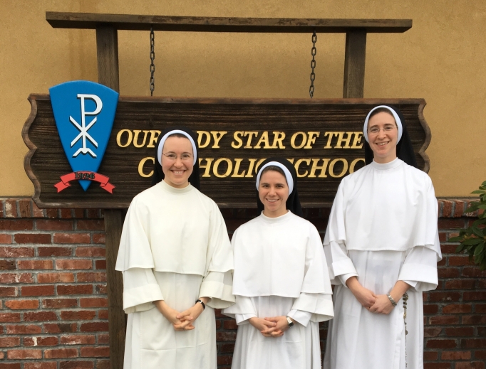 From l to r: Sister Mariana, Sister Daniela and Sister Maria Caeli pose in front of the school sign. From l to r: Sister Mariana, Sister Daniela and Sister Maria Caeli pose in front of the school sign.