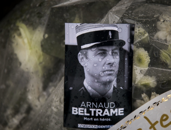 A photo of Lt. Col. Arnaud Beltrame placed on a bunch of flowers at the main gate of the police headquarters in Carcassonne, France, March 24. The French policeman, who offered himself up to an Islamic extremist gunman in exchange for a hostage, died of his injuries, raising the death toll in the March 23 attack to four. The officer, a Catholic, was honored Saturday as a national hero of 'exceptional courage and selflessness.' A photo of Lt. Col. Arnaud Beltrame placed on a bunch of flowers at the main gate of the police headquarters in Carcassonne, France, March 24. The French policeman, who offered himself up to an Islamic extremist gunman in exchange for a hostage, died of his injuries, raising the death toll in the March 23 attack to four. The officer, a Catholic, was honored Saturday as a national hero of 'exceptional courage and selflessness.'