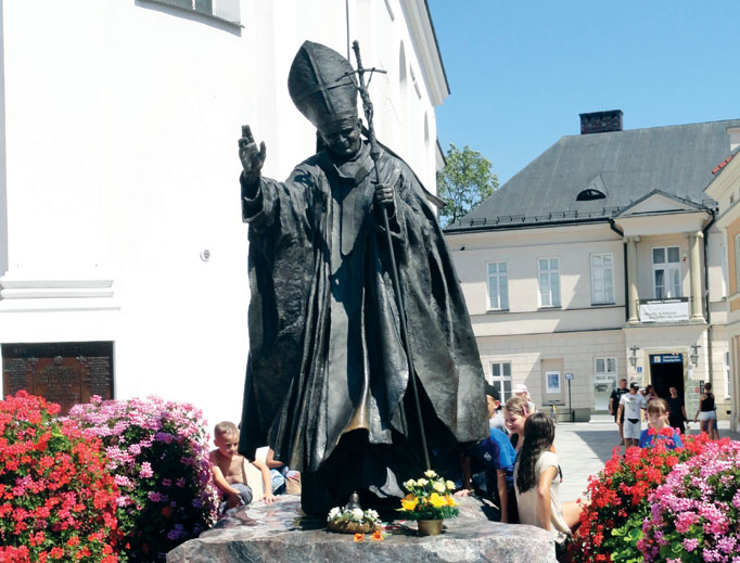 Above, a statue of John Paul II in a Wadowice square. Below, the Wadowice basilica (exterior and interior showing portrait and relics), the John Paul II Family Home Museum and the yellow house where the saint lived in Krakow. Other photos showcase displays at the Wadowice museum, including his skis and rings that John Paul II gave to Benedict XVI and a photo of the papal pair. Above, a statue of John Paul II in a Wadowice square. Below, the Wadowice basilica (exterior and interior showing portrait and relics), the John Paul II Family Home Museum and the yellow house where the saint lived in Krakow. Other photos showcase displays at the Wadowice museum, including his skis and rings that John Paul II gave to Benedict XVI and a photo of the papal pair.