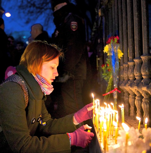 A woman lights candles in memory of the victims of clashes between police and protesters in Kiev, at the Ukrainian Embassy in Moscow on Feb. 19. A woman lights candles in memory of the victims of clashes between police and protesters in Kiev, at the Ukrainian Embassy in Moscow on Feb. 19.