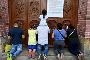 People pray at a door of the closed Basilica of the Lord of Miracles in Buga, Colombia, on March 17, after it was closed as a preventive measure against the spread of the new coronavirus, COVID-19. The Basilica of the Lord of Miracles is one of the most important and most visited religious shrines in the country. People pray at a door of the closed Basilica of the Lord of Miracles in Buga, Colombia, on March 17, after it was closed as a preventive measure against the spread of the new coronavirus, COVID-19. The Basilica of the Lord of Miracles is one of the most important and most visited religious shrines in the country.