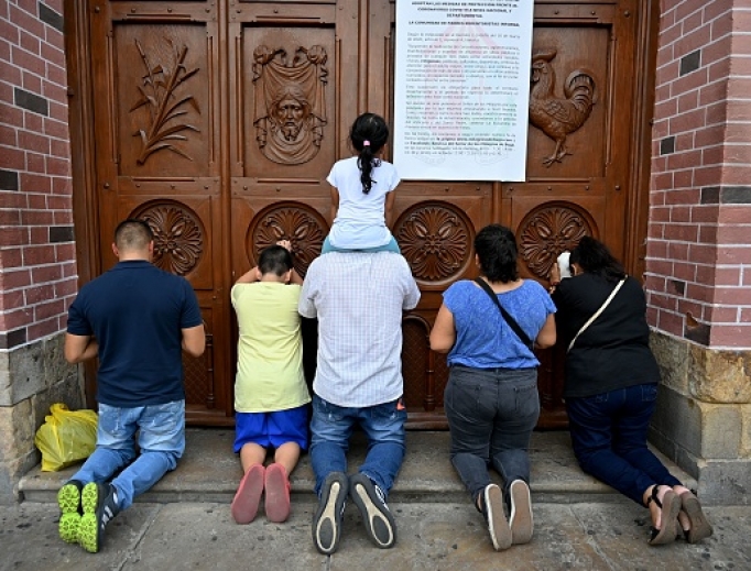 People pray at a door of the closed Basilica of the Lord of Miracles in Buga, Colombia, on March 17, after it was closed as a preventive measure against the spread of the new coronavirus, COVID-19. The Basilica of the Lord of Miracles is one of the most important and most visited religious shrines in the country. People pray at a door of the closed Basilica of the Lord of Miracles in Buga, Colombia, on March 17, after it was closed as a preventive measure against the spread of the new coronavirus, COVID-19. The Basilica of the Lord of Miracles is one of the most important and most visited religious shrines in the country.