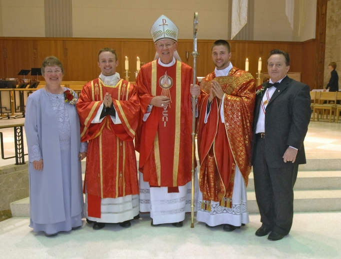 Father Justin (next to his mother) and Father Joshua Waltz (next to his father), shown with their parents, Herb and Theresa. Bishop Paul Zipfel presided at the Cathedral of the Holy Spirit in Bismarck, North Dakota. Below, framed manutergia in the Waltz home: one is behind, showing around the edges. Also shown: Father Jordan Dosch at his first Mass, June 1, at Cathedral of the Holy Spirit, presents the special cloth to his mother, Lynne Dosch. He had just explained the custom before presenting it to his mother. His father, Vernon, is to the left of Lynne.
Father Justin (next to his mother) and Father Joshua Waltz (next to his father), shown with their parents, Herb and Theresa. Bishop Paul Zipfel presided at the Cathedral of the Holy Spirit in Bismarck, North Dakota. Below, framed manutergia in the Waltz home: one is behind, showing around the edges. Also shown: Father Jordan Dosch at his first Mass, June 1, at Cathedral of the Holy Spirit, presents the special cloth to his mother, Lynne Dosch. He had just explained the custom before presenting it to his mother. His father, Vernon, is to the left of Lynne.