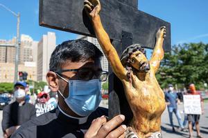 A seminarian holds a crucifix in Detroit during a protest Sunday in memory of George Floyd. A seminarian holds a crucifix in Detroit during a protest Sunday in memory of George Floyd.