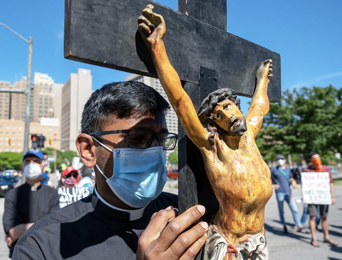 A seminarian holds a crucifix in Detroit during a protest Sunday in memory of George Floyd. A seminarian holds a crucifix in Detroit during a protest Sunday in memory of George Floyd.