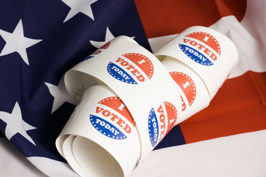 Voting stickers spiral against an American flag. Voting stickers spiral against an American flag.