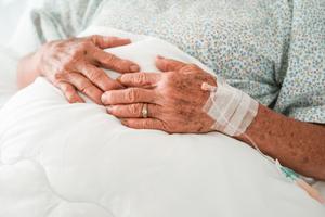An elderly woman sits in a hospital bed. An elderly woman sits in a hospital bed.