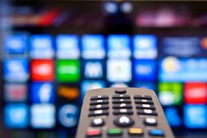 A remote control with streaming options in the background. A remote control with streaming options in the background.