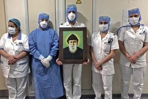 In a picture taken by a nurse on April 9, 2020, at the Hôtel Dieu de France Hospital in Beirut, Lebanon, medical workers carry a picture of St. Charbel in the COVID-19 section of the hospital. In a picture taken by a nurse on April 9, 2020, at the Hôtel Dieu de France Hospital in Beirut, Lebanon, medical workers carry a picture of St. Charbel in the COVID-19 section of the hospital.