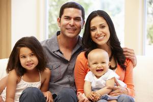Hispanic family of four poses with their young baby. Hispanic family of four poses with their young baby.