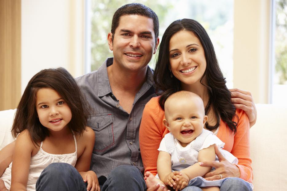 Hispanic family of four poses with their young baby. Hispanic family of four poses with their young baby.