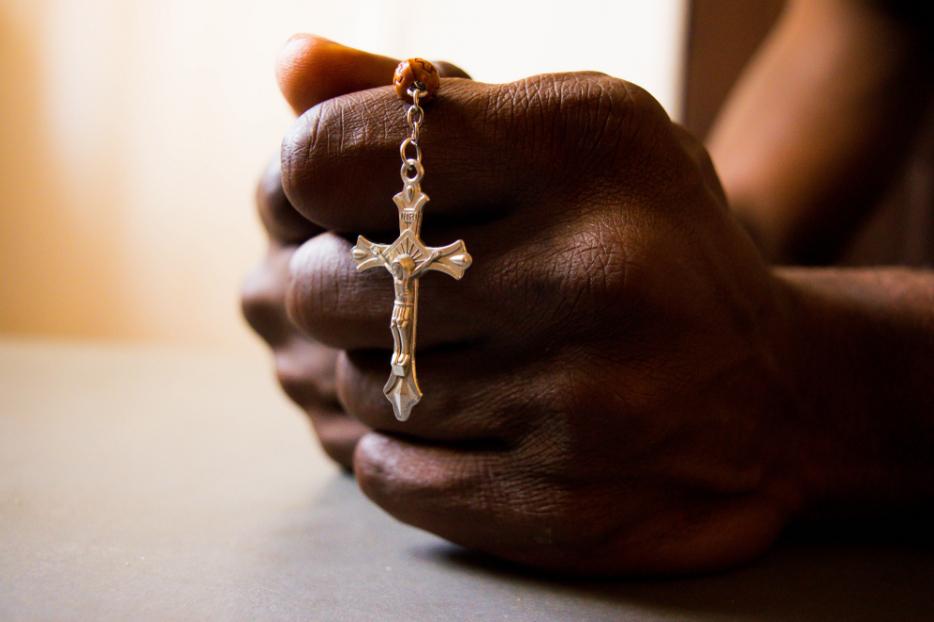 A Nigerian man holds a crucifix. A Nigerian man holds a crucifix.