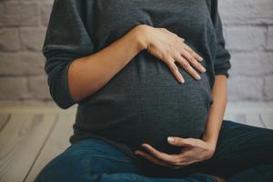 A pregnant sits on the floor. A pregnant sits on the floor.