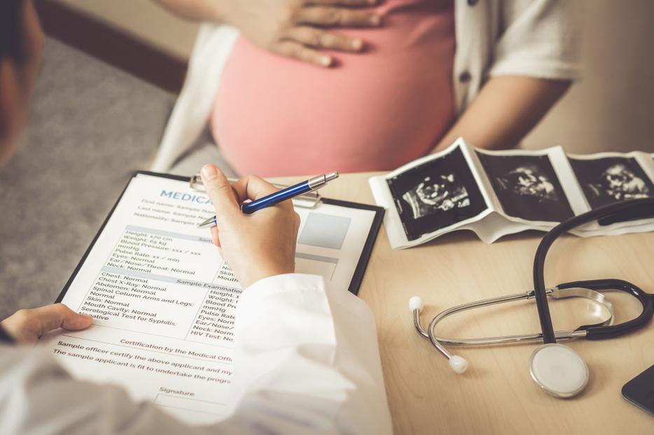 A pregnant woman meets with her doctor. A pregnant woman meets with her doctor.