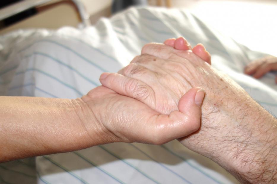 A daughter holds her mother's hand in the hospital. A daughter holds her mother's hand in the hospital.