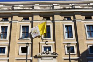 Building with the flag of the Vatican and the Vatican Coat of Arms in Vatican City. Building with the flag of the Vatican and the Vatican Coat of Arms in Vatican City.