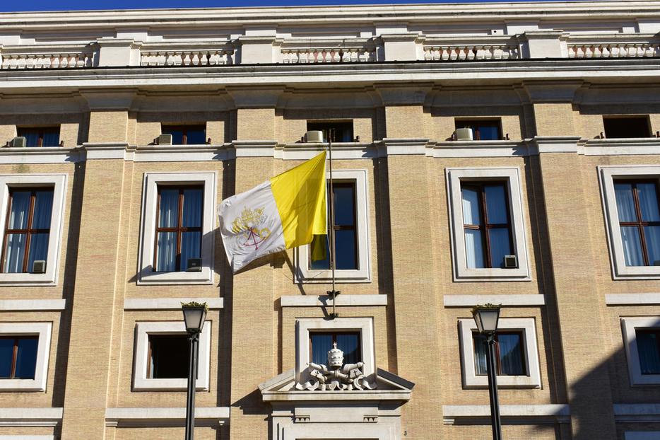 Building with the flag of the Vatican and the Vatican Coat of Arms in Vatican City. Building with the flag of the Vatican and the Vatican Coat of Arms in Vatican City.