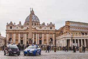 A crowd of people and police cars in front of St. Peter's Square. A crowd of people and police cars in front of St. Peter's Square.