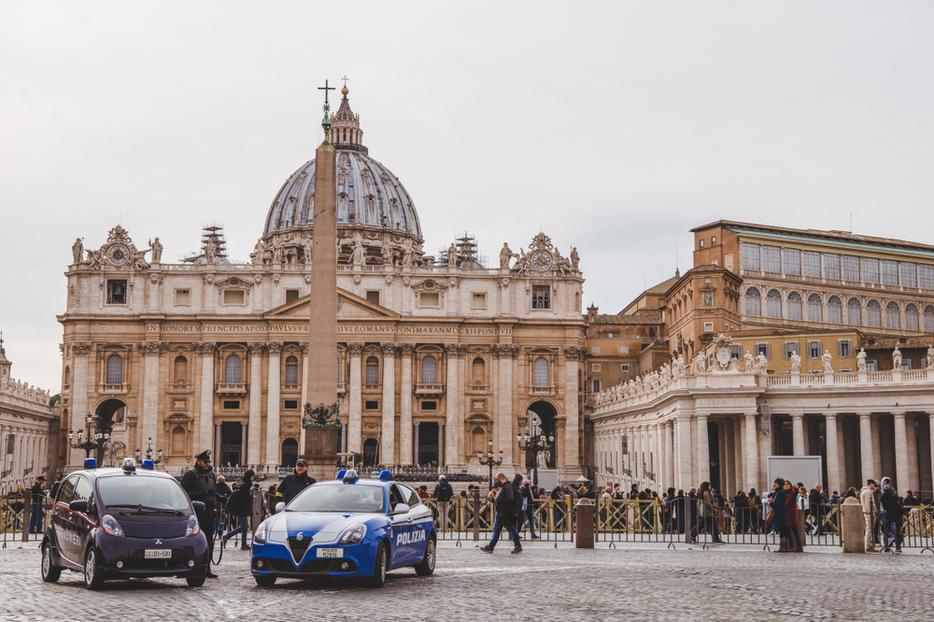 A crowd of people and police cars in front of St. Peter's Square. A crowd of people and police cars in front of St. Peter's Square.