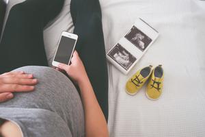 A pregnant woman relaxes on her bed next to an ultrasound. A pregnant woman relaxes on her bed next to an ultrasound.