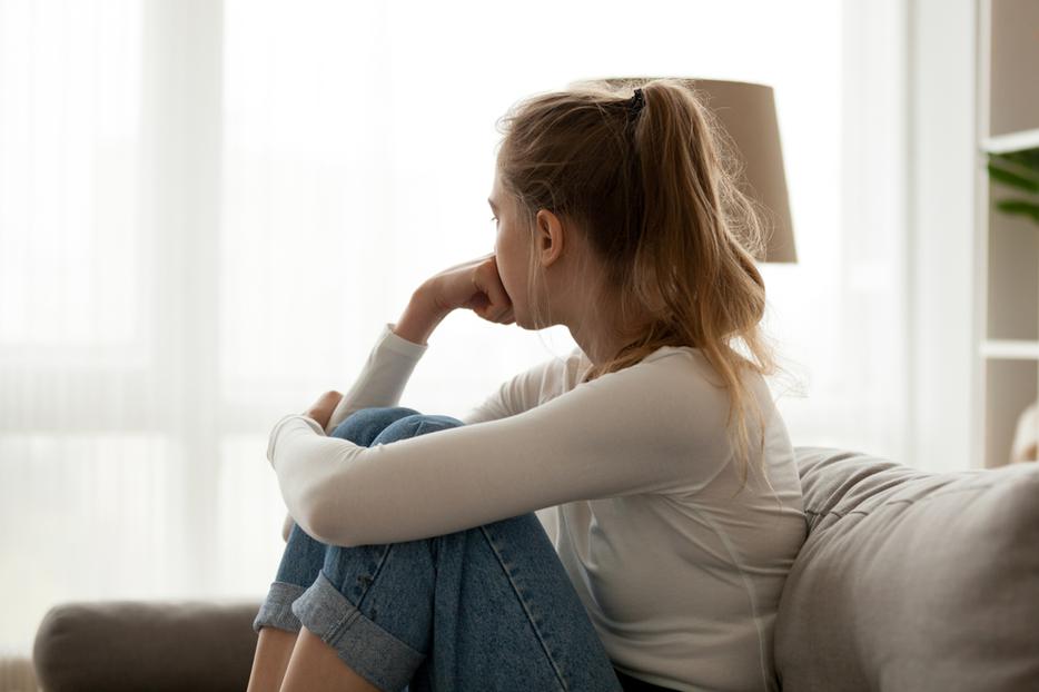 A young woman sits looking out the window contemplating an abortion. A young woman sits looking out the window contemplating an abortion.